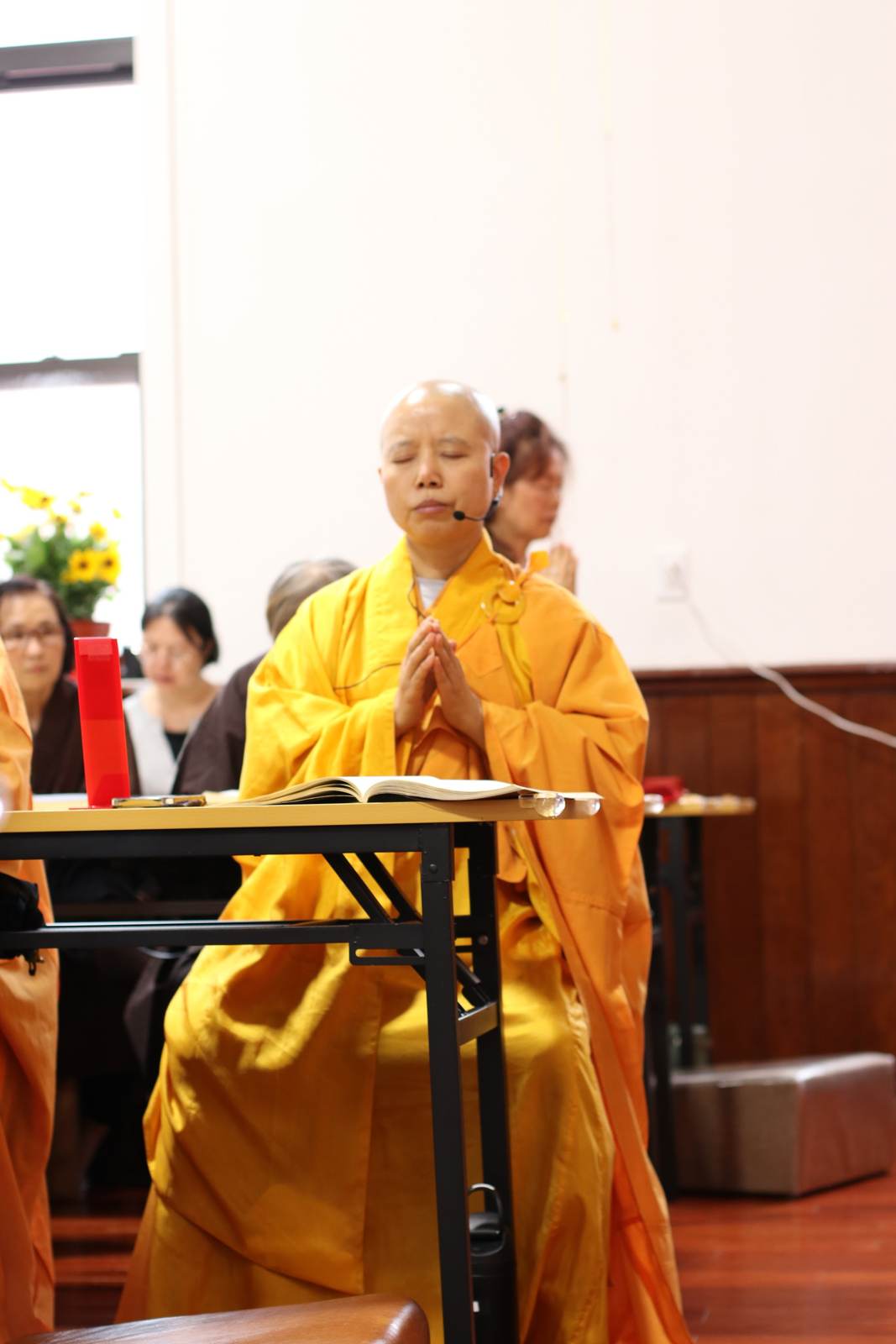 The founder, palms joined in prayer during a service